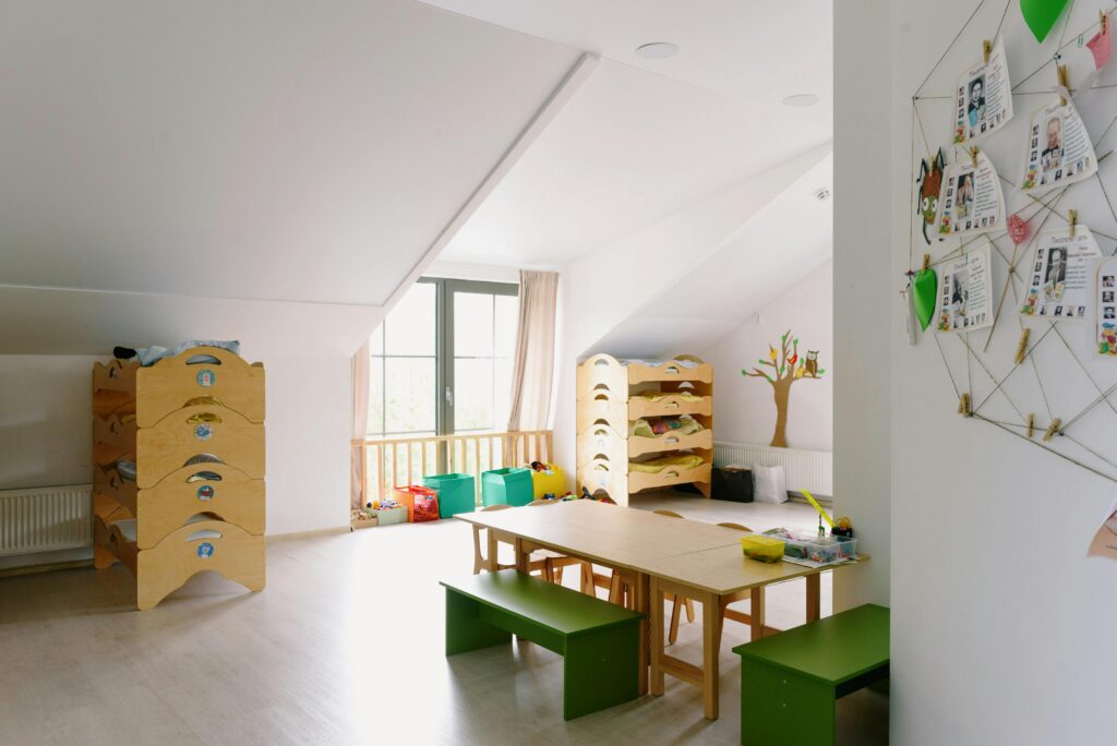 A well-lit and organized kindergarten room with wooden furniture and playful decor.